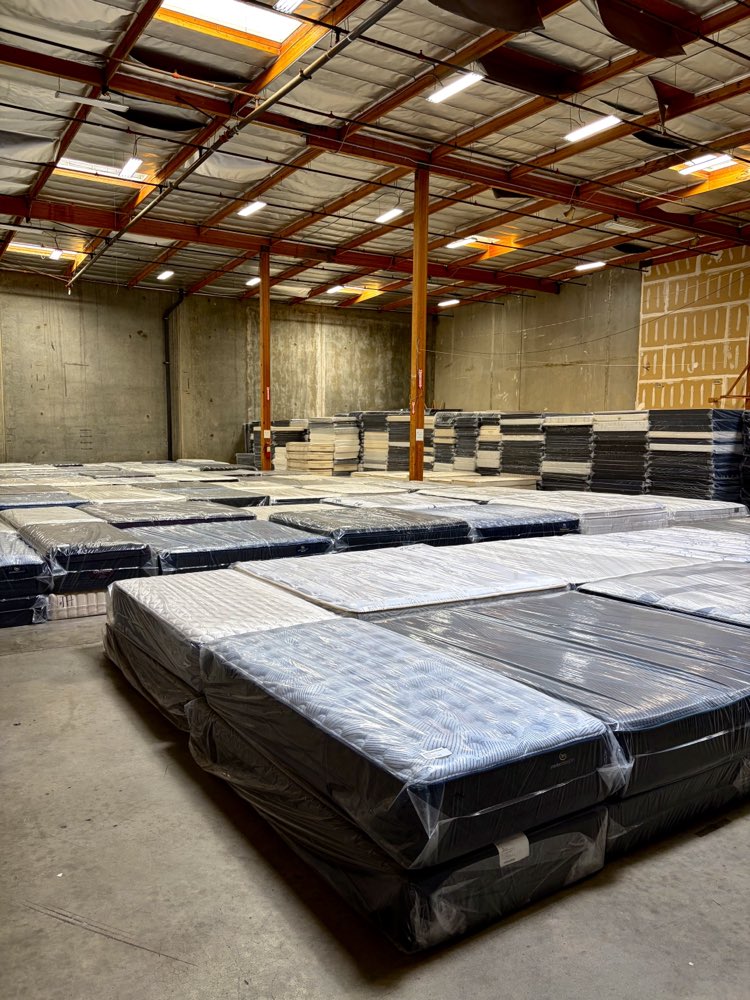 Rows of wrapped mattress sets on the warehouse floor at Mattress Liquidation in Rancho Cucamonga
